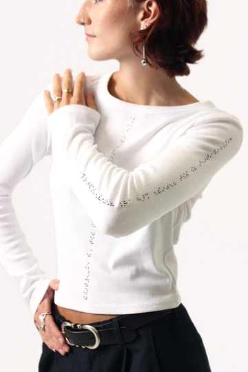 Woman wears white long sleeve t shirt with braille down the centre and on the sleeve in black